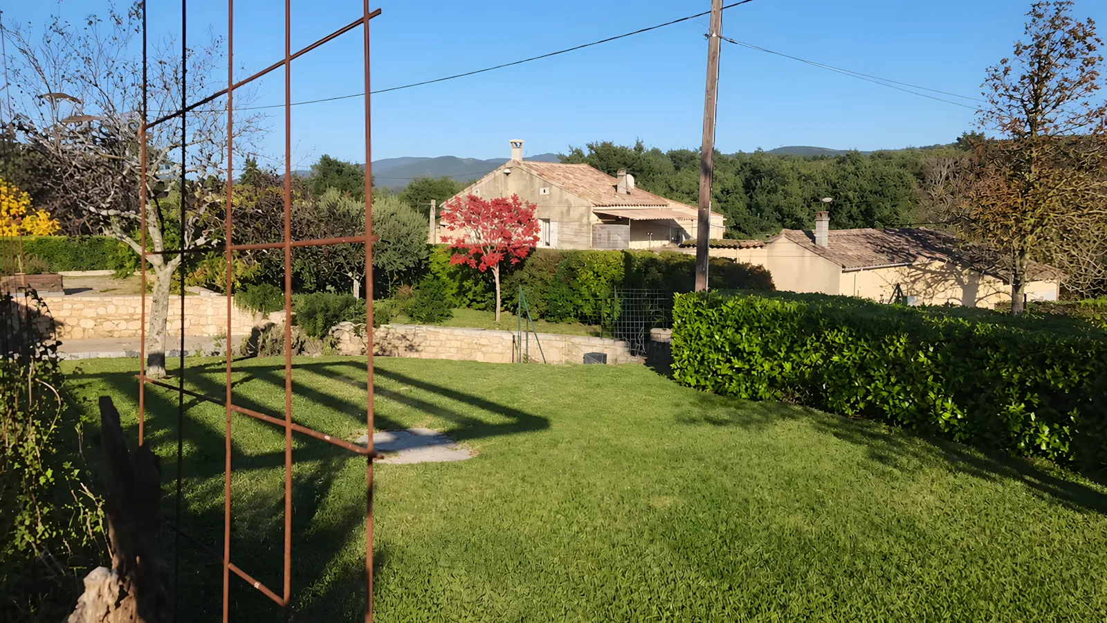 Pelouse tondue et haies taillées autour d’une maison de caractère en Ardèche méridionale